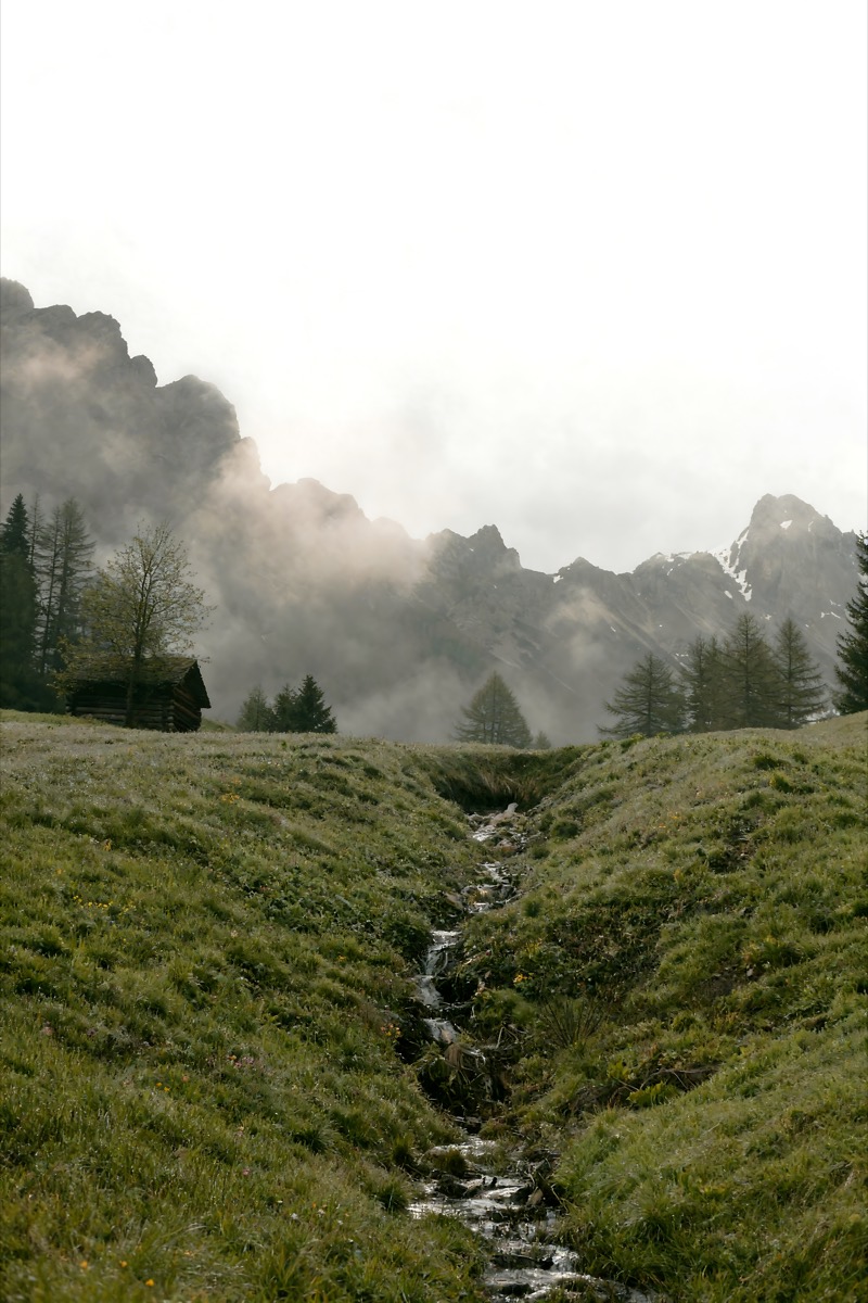 Small wooden bridge over a stream with mountains behind